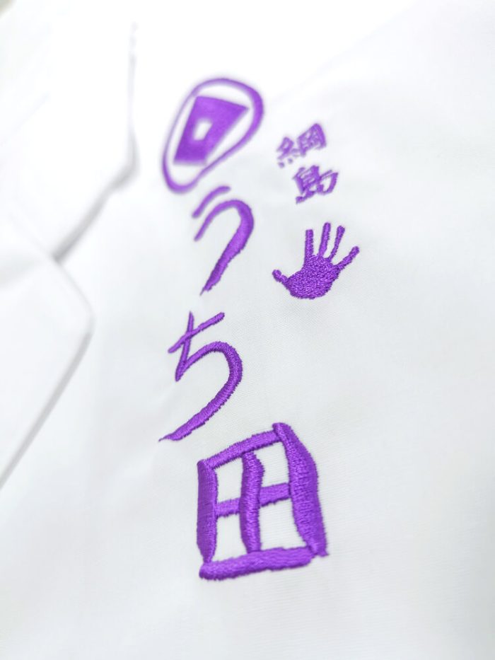 厨房白衣への紫糸で名入れしたロゴ刺繍部分
